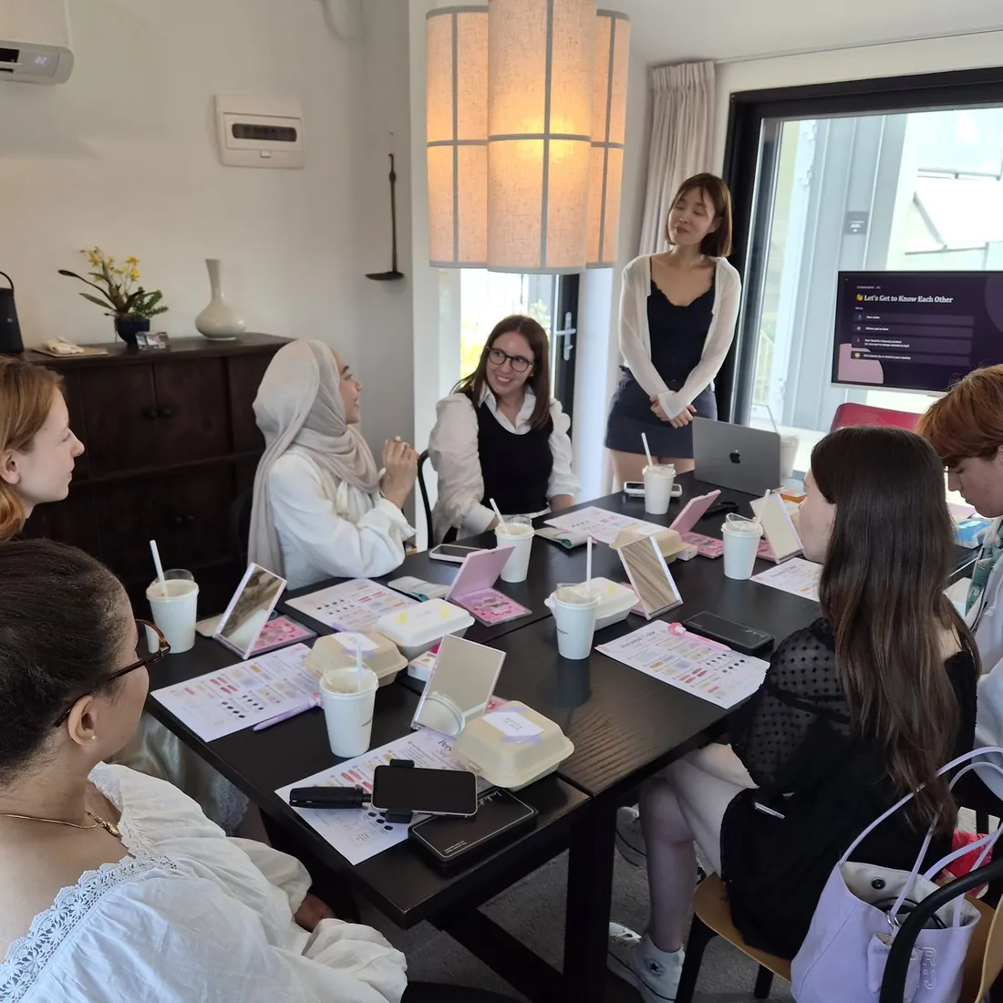 The group around the table mid-session, worksheets and products out