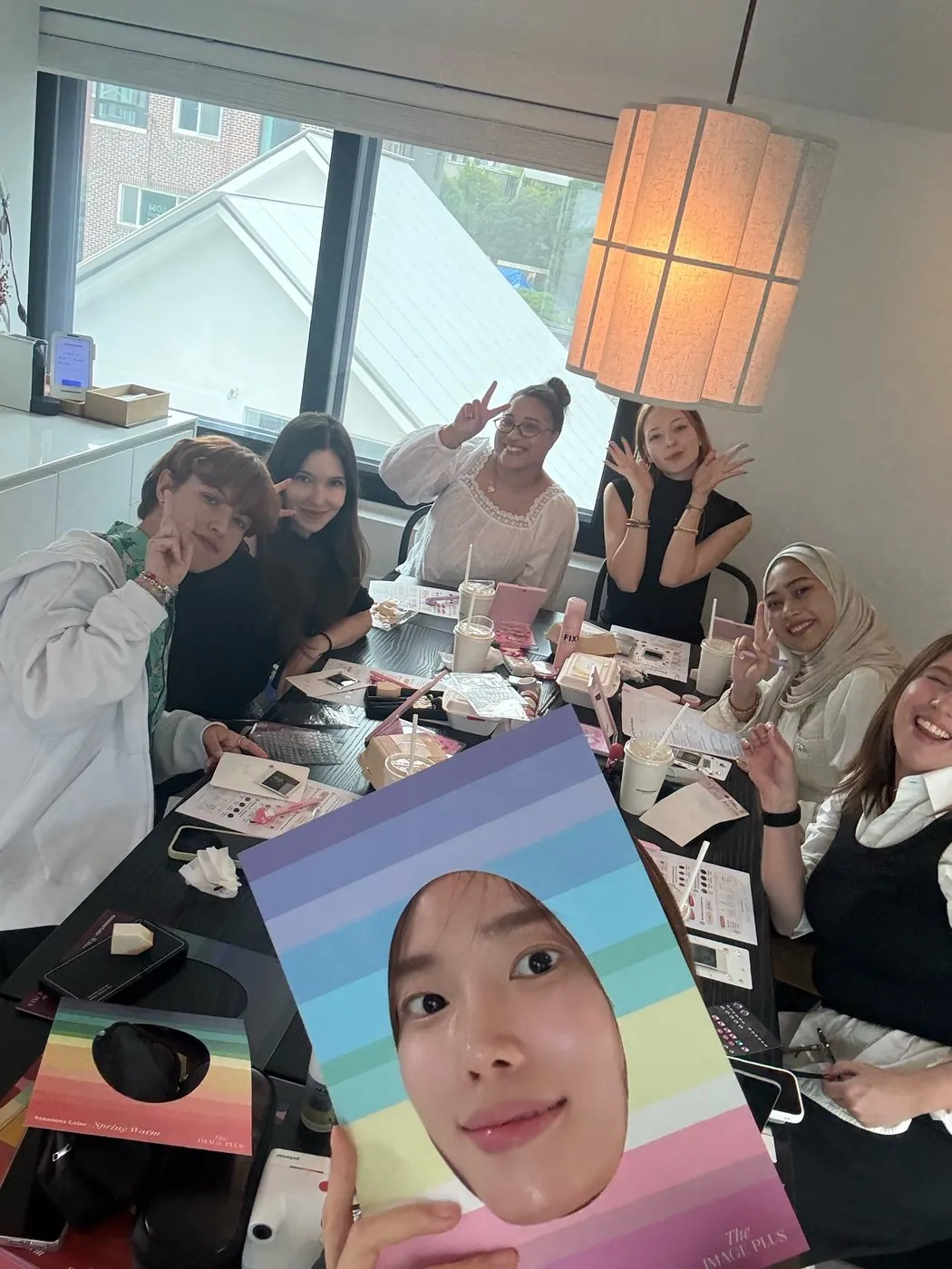The group around the table at a Beauty Play session, holding up a personal colour drape